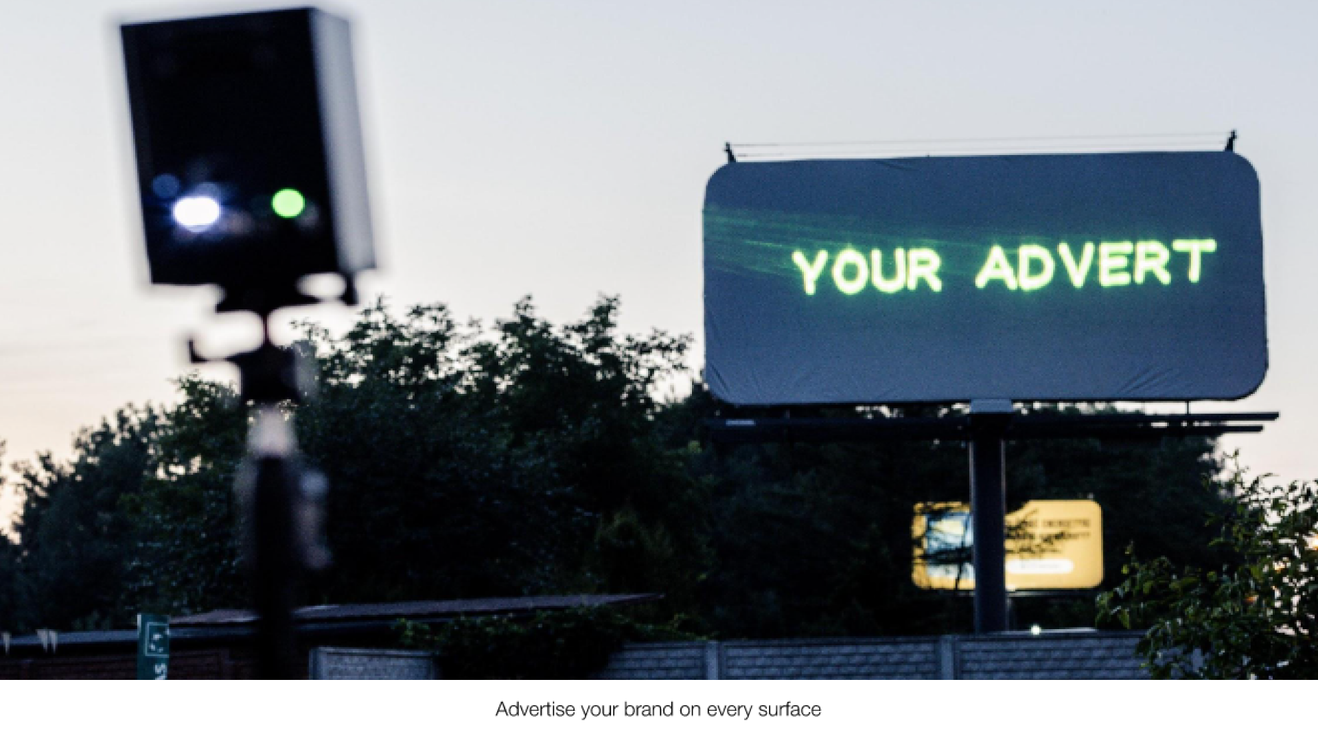 A blank outdoor billboard with the text "your advert" projected onto it from a Lasercube laser projector, showcasing how it can be used for outdoor advertising