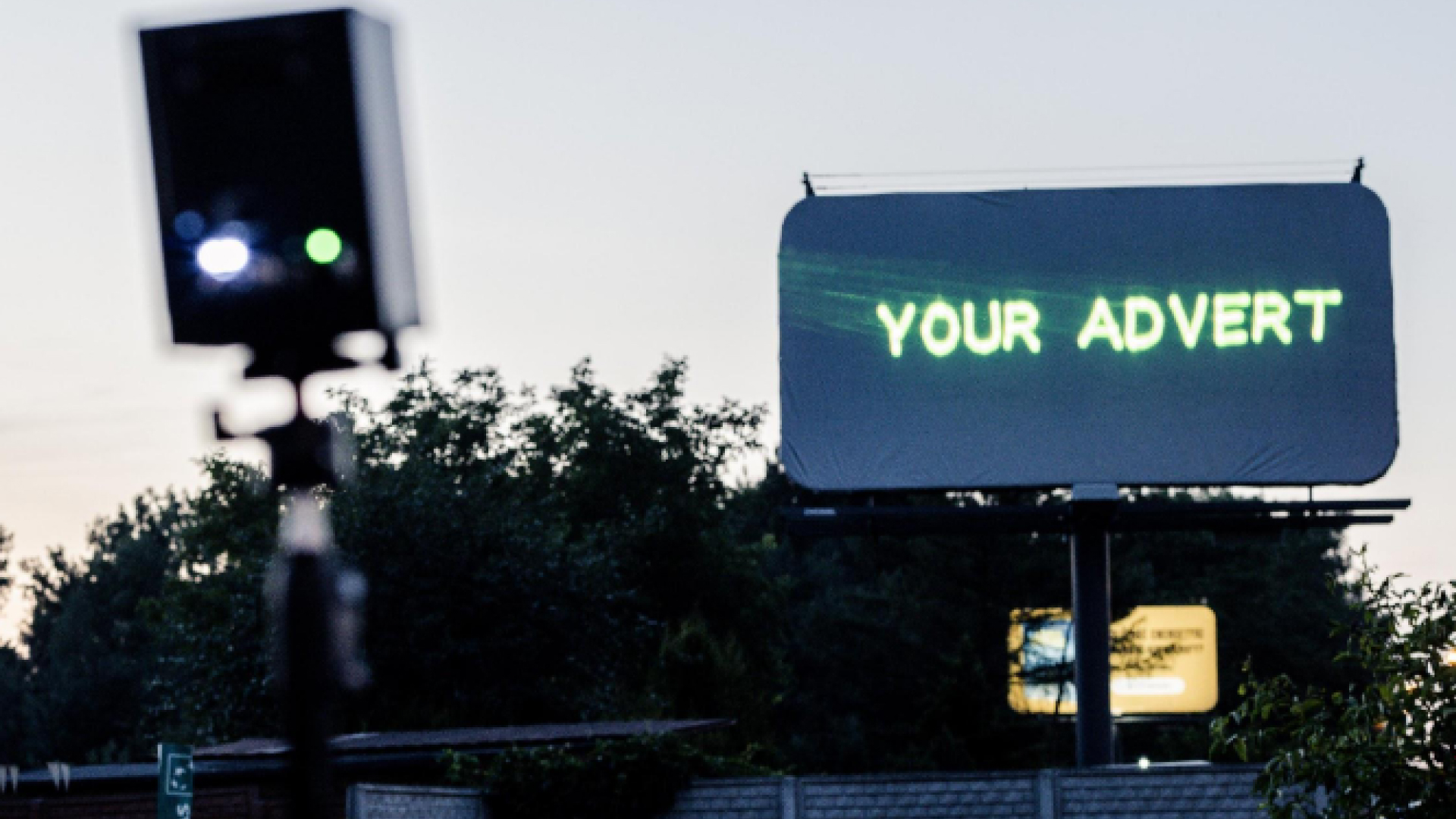 A blank outdoor billboard with the text "your advert" projected onto it from a Lasercube laser projector, showcasing how it can be used for outdoor advertising