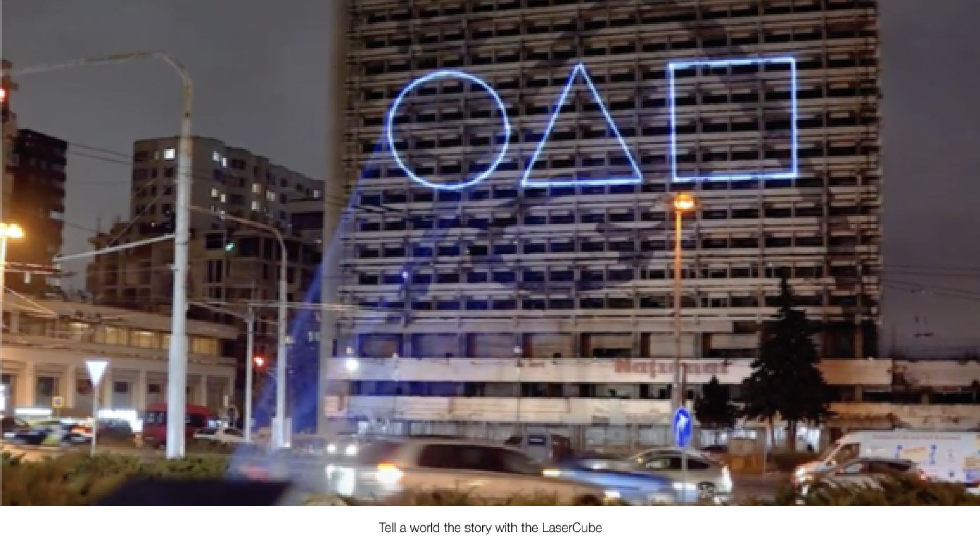 Laser lights being shown in an outdoor laser advertising environment, projecting blue laser lights from a laser cube on the road.