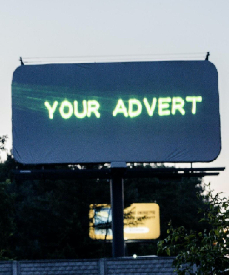 A blank outdoor billboard with the text "your advert" projected onto it from a Lasercube laser projector, showcasing how it can be used for outdoor advertising