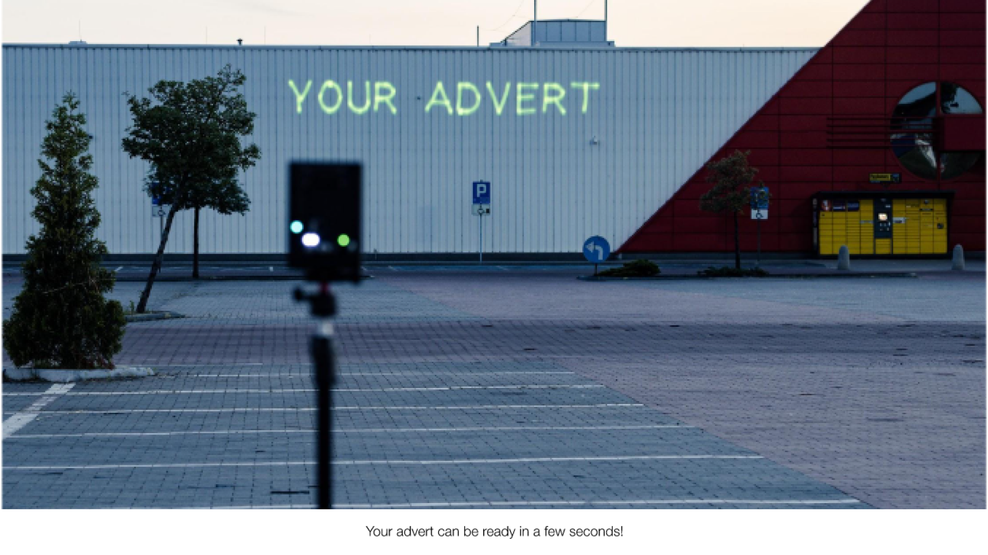 A small white building with the text "your advert" projected onto it from a Lasercube laser projector, showcasing how it can be used for outdoor advertising