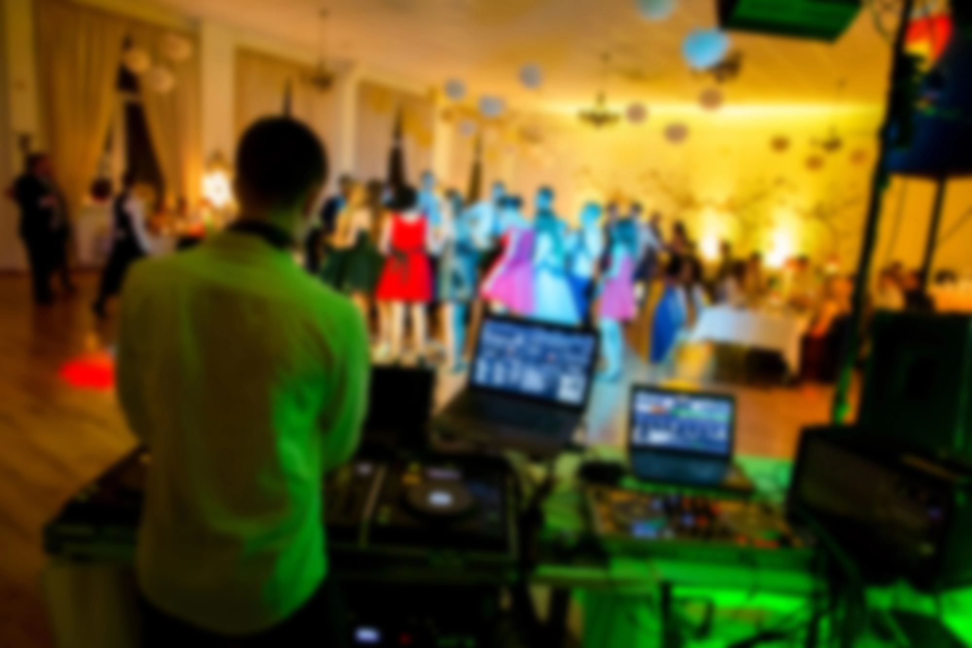 DJ at a wedding reception playing with wedding laser lights, with a crowd behind DJ at a wedding reception playing with wedding laser lights, with a crowd behind