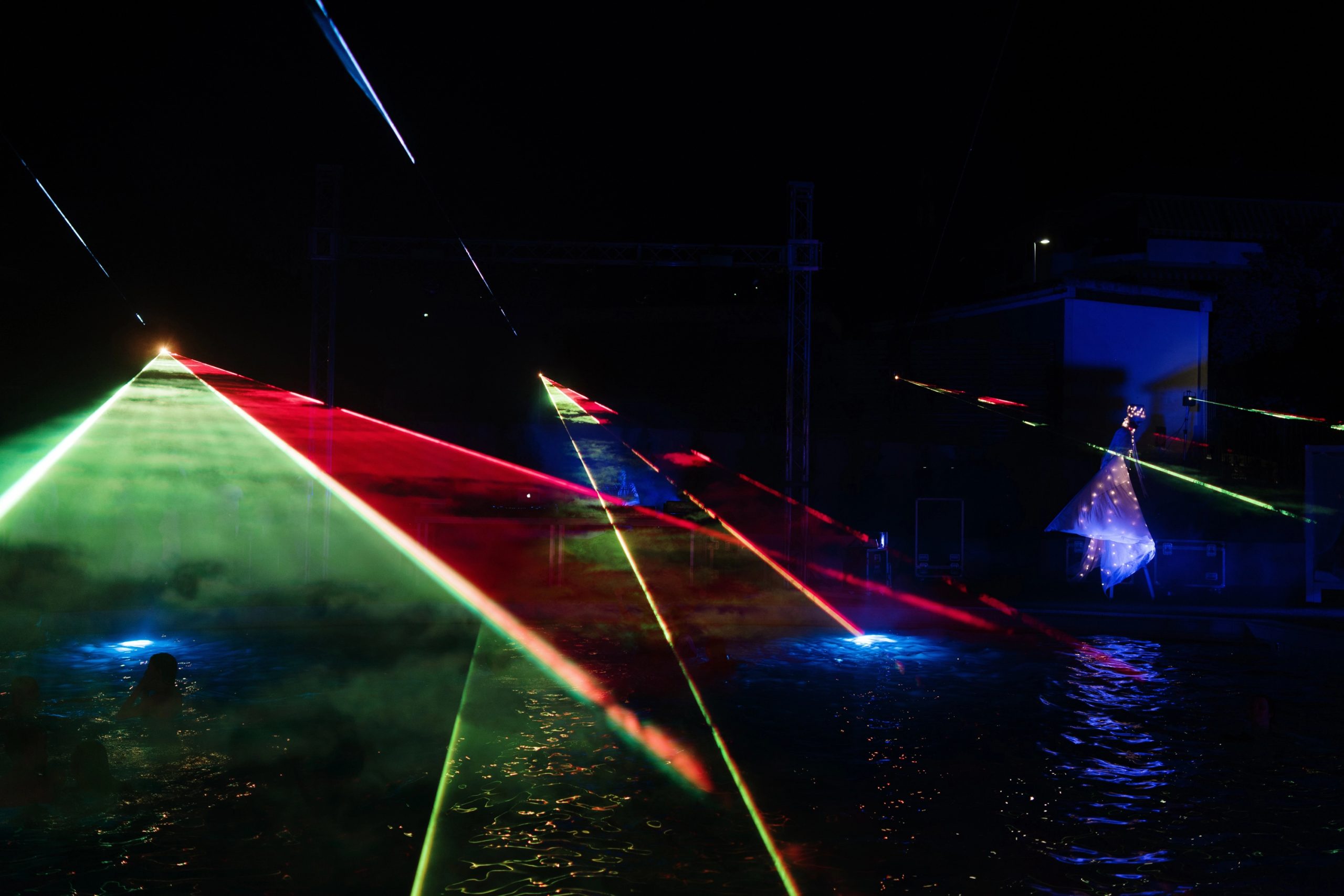Lights game during the dj set while man in white and bright costume dances by the pool